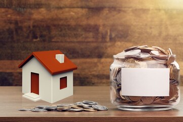 Canvas Print - Family budget concept. Big jar with coins and toy house