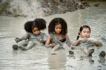 Group of happy children girl playing in wet mud puddle on summer day in rainy season