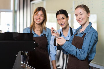 Portrait of young barista woman preparing coffee for customer in the cafe shop. Group of female waitress service coffee at cafe shop