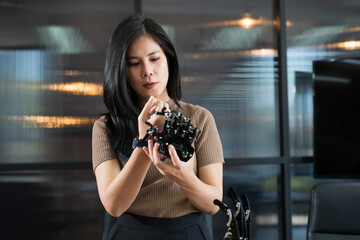 Asian female engineer working with AI robot arm system. Female engineer control robot arm with her hands. Asian female constructing robot arm system project. Programmable logic controller concept