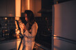 © polinaloves - Beautiful girl in the kitchen using a smartphone.