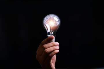 businessman Hand holding light bulb with brain glowing with orange light line and ray. Creative and new business knowledge thinking idea concept.