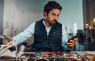 Poster - Computer hardware repair, phone and it worker watch a diy video to fix a semiconductor and circuit. Engineering, workshop and electric work of a male engineer with a mobile doing electrical project