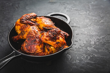 Wall Mural - Roasted half chicken in pan on black background