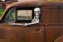 Human Skeleton Sitting In A Rusty Old Car And Looking Out Of The Window