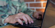 © chinnarach - close up soldier man hand typing on keyboard laptop to check and use command for military operation test system in office room concept