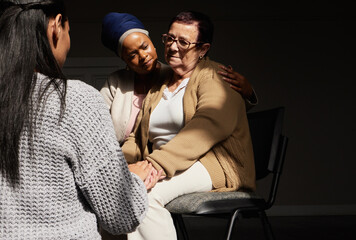 Support, holding hands and senior woman in group therapy with women understanding, sharing feelings and talking in session. Mental health, grief or depression, people with therapist sitting together.