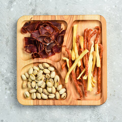 Wall Mural - Snacks for beer. Pistachios, cheese, sausages and dried meat. On a wooden plate. Rustic style.