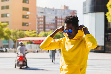 Young black man in sunglasses adjusting hood