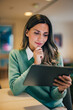 © bnenin - Smiling businesswoman using a digital tablet, sitting at the home office, elegantly dressed.