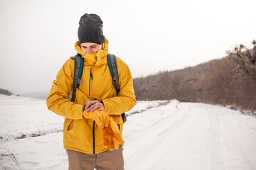 Wall Mural - The man dresssed yellow warm jacket and trousers, bagpack traveling in the snow landscape