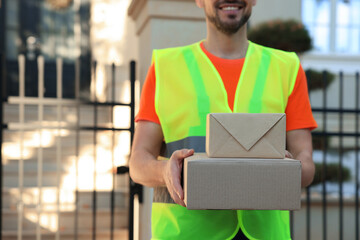 Canvas Print - Courier in uniform with parcels outdoors, closeup. Space for text