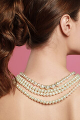 Poster - Young woman wearing elegant pearl necklace on pink background, back view