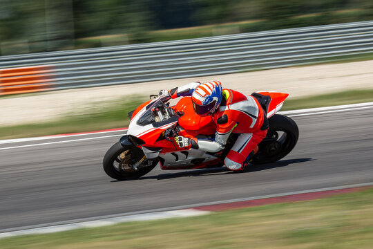 a motorcycle rider riding on an white,orange sport motorcycle through a corner at high speed. leanin