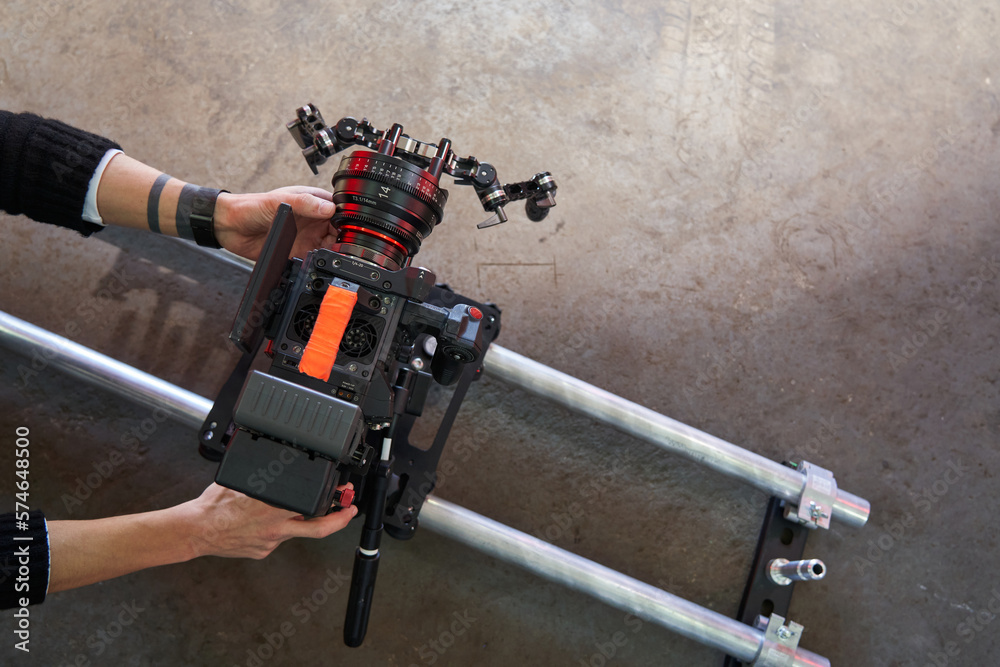 Male hands of a videographer roll and set up a professional movie ...
