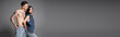 © LIGHTFIELD STUDIOS - shirtless tattooed man and trendy asian woman posing with hands in back pockets of jeans on grey background, banner.