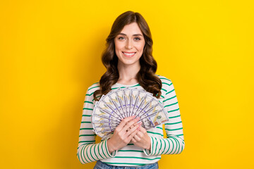 Sticker - Photo portrait of lovely young lady holding money fan rich successful dressed stylish striped clothes isolated on yellow color background