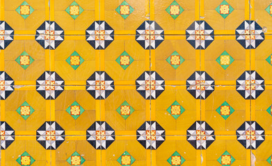 Wall Mural - Fragment of building wall with yellow floral ceramic wall tiles Azulejo Abstract decorative background textured ornate pattern. Traditional ornate Portuguese architecture 