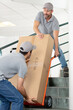 two male young movers carrying box climbing steps