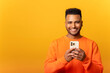 © Vadim Pastuh - Photo of handsome cheerful smiling man holding mobile phone in the hand and smiling, isolated over yellow background, chatting using smartphone in front camera