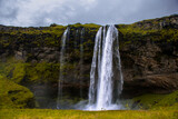 Fototapeta Tęcza - Seljalandsfoss Iceland is a stunning waterfall that allows visitors to walk behind the cascading water.