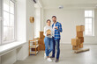 Full-size shot of happy married couple holding keys to their new modern spacious apartment and mock-up of toy house. Family couple looks into camera and are happy about their purchase of real estate.