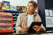 © kleberpicui - Elderly man working in a hardware store using digital tablet. Small business concept.