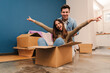 © Jose Calsina - Young caucasian happy couple having fun playing with cardboard box in their new house after moving. Husband and wife arriving at their new home with packages enjoying the change . Loan concept. High