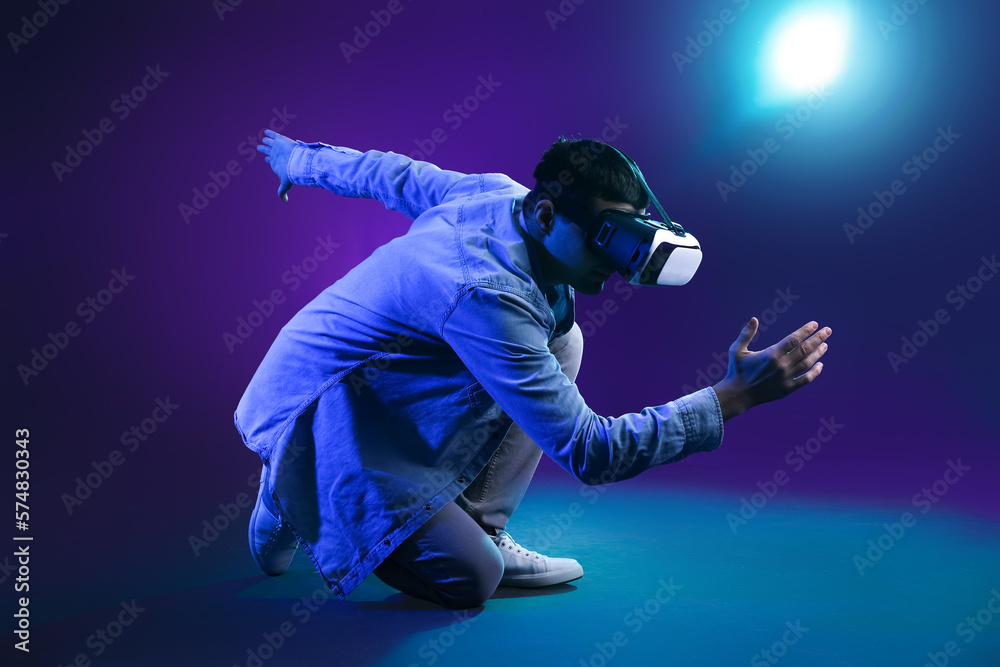 Young man using VR glasses on dark color background