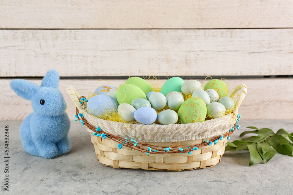 Basket with painted Easter eggs and toy bunny on light table