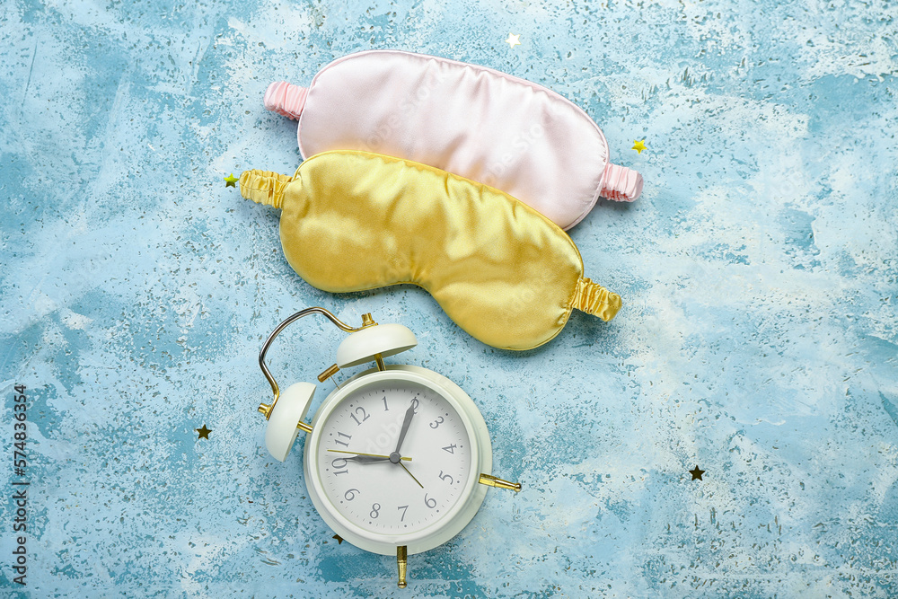 Sleeping masks and alarm clock on color background. World Sleep Day concept