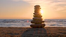 Balanced Pebble Pyramid Silhouette On The Beach On Sunset With Sea On The Background. Zen Stones On The Sea Beach With Sun Beam, Meditation, Spa, Harmony, Calmness, Balance Concept.
