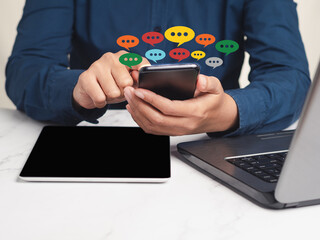 Wall Mural - close-up of hands using mobile phone with colorful chat icons on application communication digital
