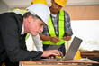 © bongkarn - Caucasian businessman using a laptop while working with a team of construction engineers