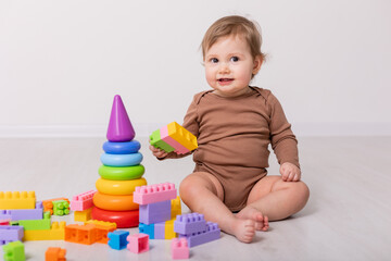 adorable baby in brown shirt playing with toys, card, banner, space for text