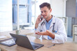 © Sharne T/peopleimages.com - Man, doctor and phone call with laptop in Telehealth for healthcare consulting, advice or help at office desk. Male medical professional on smartphone by computer explaining medicare or diagnosis