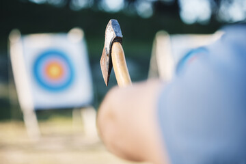 Man throwing axe at sports range, archery training or practice with board circle for goal, game and exercise. Strong person closeup with weapon for tomahawk competition, gaming park and eye target