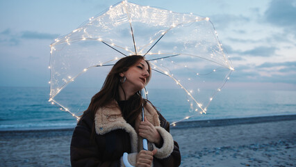 Wall Mural - Glowing umbrella of a girl walking on the beach in the night outdoor