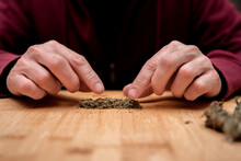 Unrecognizable Man Preparing Dried Cannabis For Making Joint