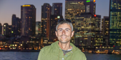 Canvas Print - Portrait of a happy caucasian man visiting Sydney at night with city skyline on the background