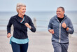Fitness, running and happy senior couple by ocean for exercise, healthy body and wellness in retirement. Sports, marriage and elderly man and woman smile for run, cardio workout and training outdoors