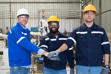 Wall Mural - Group of male engineer workers standing and putting hands together at production line in the industry factory