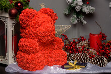Close-up Of A Red Teddy Bear Made Of Roses On A Table Next To Assorted Christmas Decorations