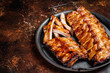 BBQ pork spare ribs St Louis with hot honey marinade in a steel tray. Dark background. Top view. Copy space