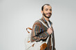 © LIGHTFIELD STUDIOS - smiling bearded student in colorful shirt standing with backpack isolated on grey.