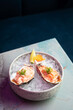 Salmon and scallop tartare served in oyster shell on ice. Raw fish dish at modern, stylish Japanese sushi restaurant. Fresh seafood with roe or caviar, ponzu and lemon in bowl on the table. Copy space