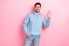 Photo Of Sweet Friendly Man Wear Blue Hoodie Smiling Waving Arm Palm Smiling Isolated Pink Color Background