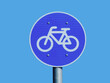 isolated blue circular bicycle route road and traffic sign. white border. bicycle symbol and icon indicating dedicated bicycle path and cycling lane. blue sky background. sports and recreation concept