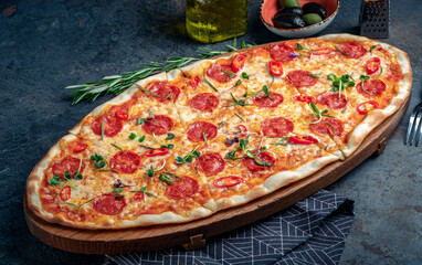 Wall Mural - Spicy long pepperoni pizza with sausage and pepper. Italian extra-size pizza served on a wooden board