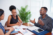 © Meeko Media - Three business colleagues discuss financial reports around boardroom table